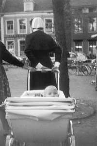 853945 Afbeelding van een zuster van het Wilhelmina Kinderziekenhuis met een kinderwagen op het Janskerkhof te Utrecht.